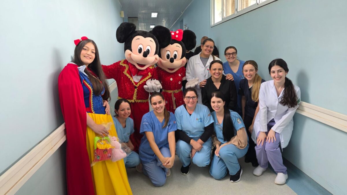 Personagens infantis e profissionais de saúde reunidos no corredor do Hospital da Criança, em Chapecó