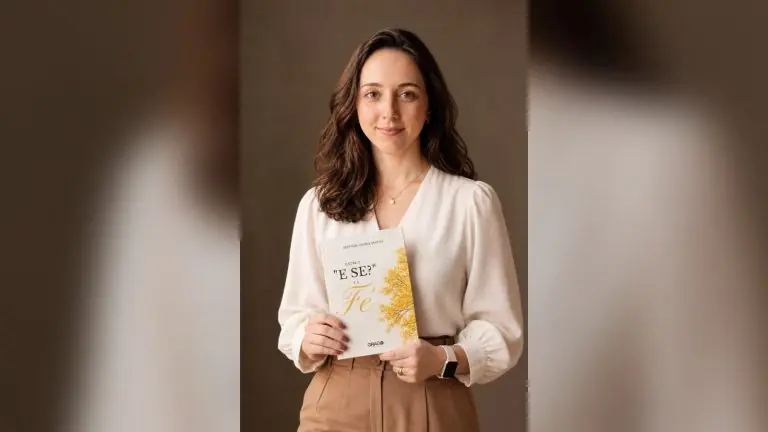 A escritora Amanda Vieira Matos segura o livro “Entre o ‘e se?’ e a Fé”