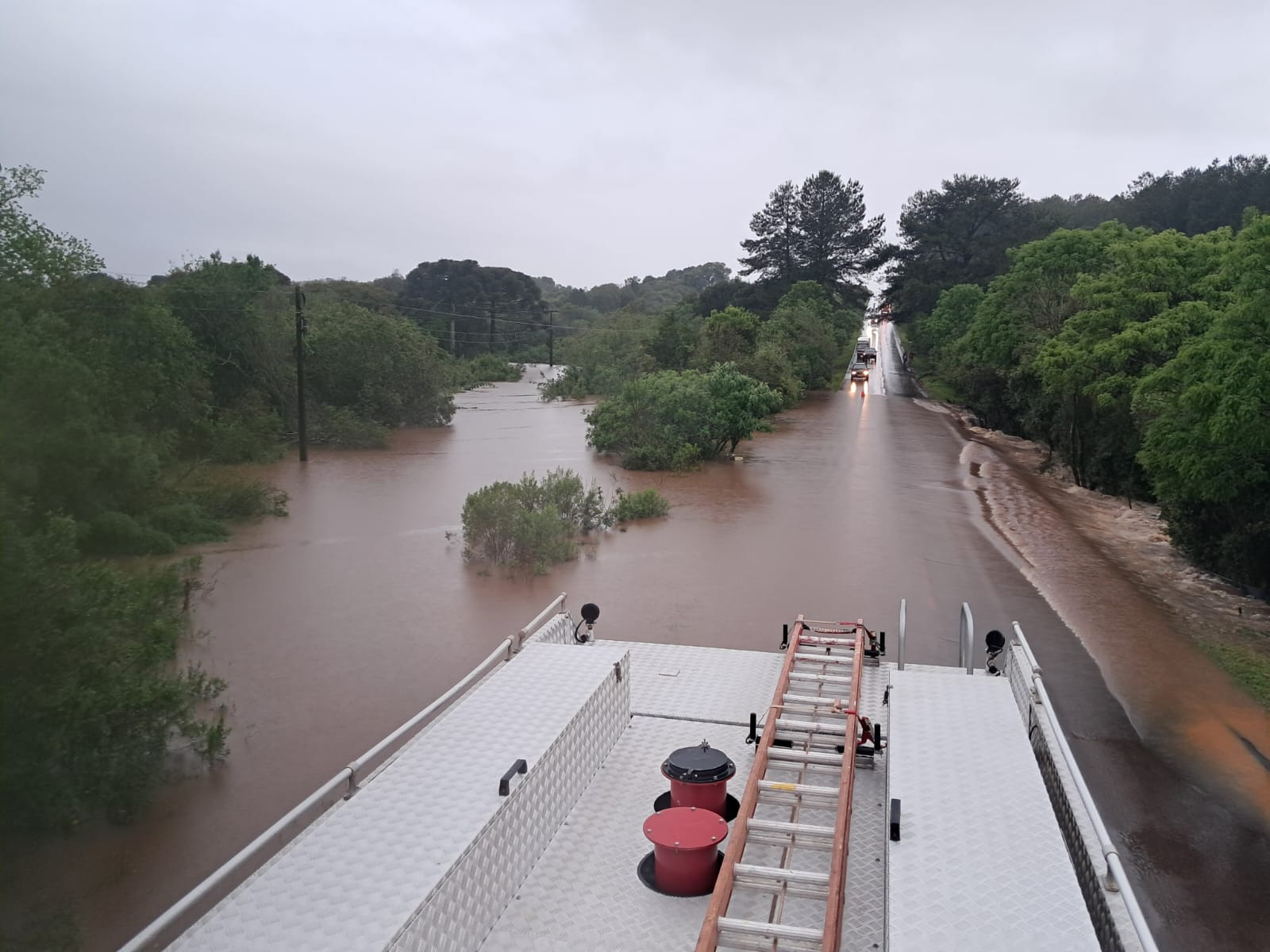 Trecho de rodovia tomado pela água da chuva, visto do alto de um caminhão dos bombeiros