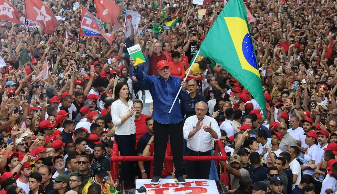 Lula acena para apoiadores com a Constituição em uma das mãos durante comemoração da reeleição