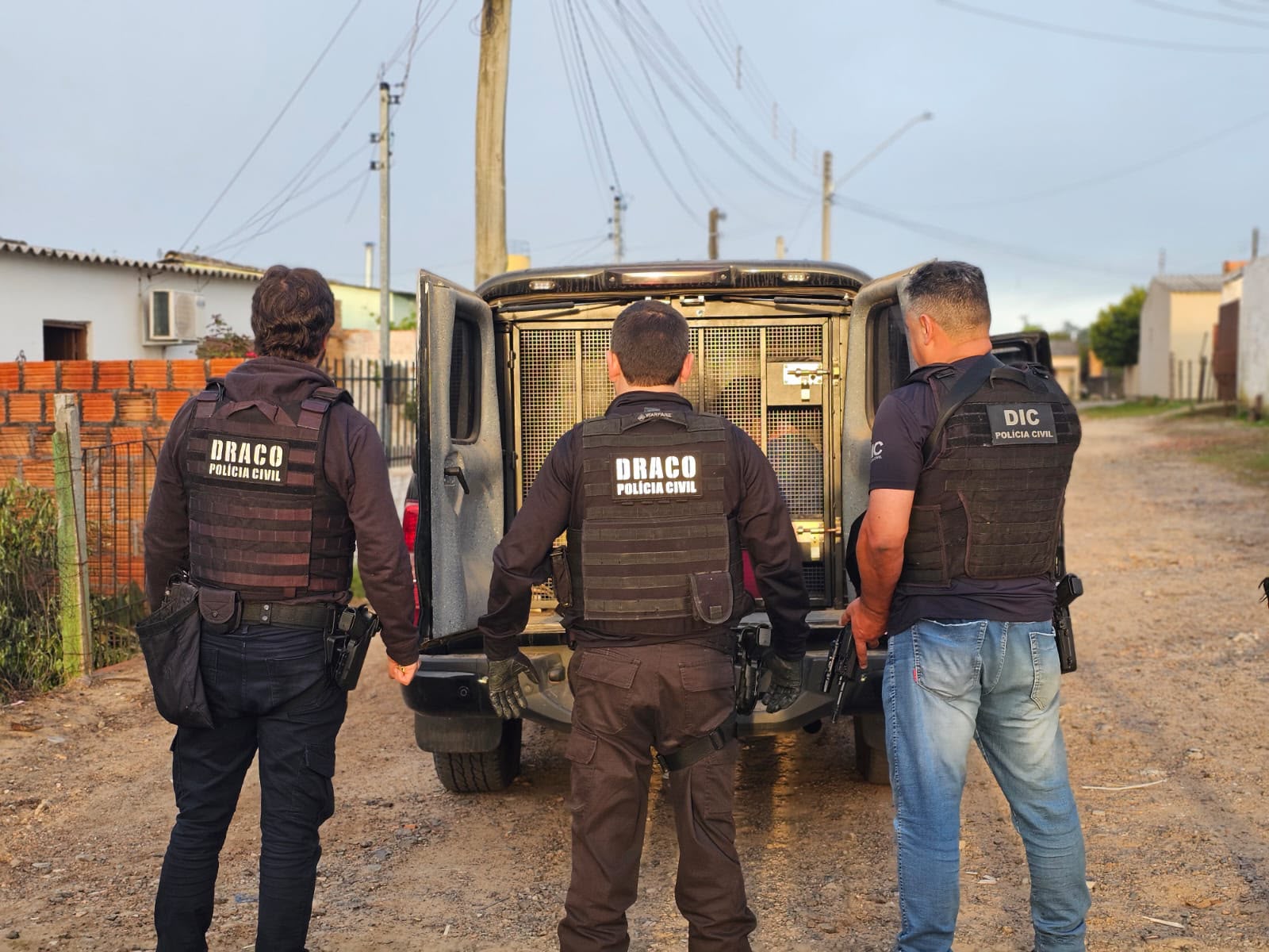 Policiais civis da Draco e da DIC diante de viatura durante a Operação Trabalho Interno, em Dom Pedrito (RS)