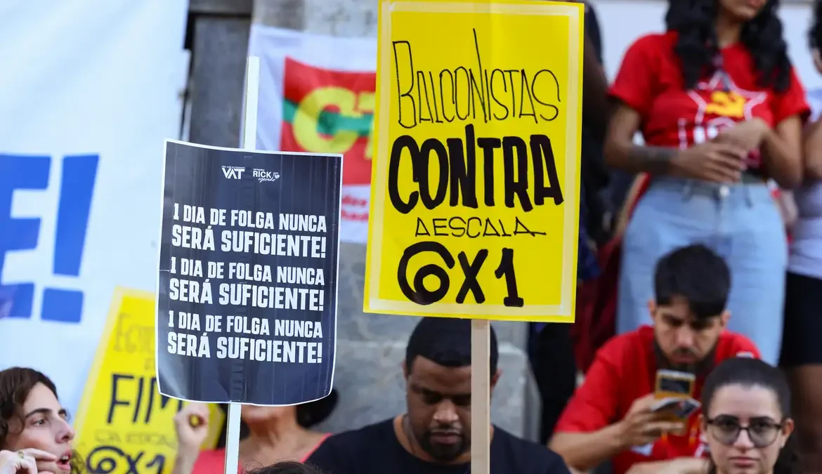 Manifestantes com cartazes contra a escala 6x1 em ato pelo fim da jornada